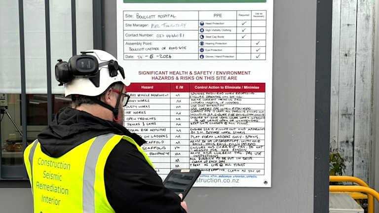A man in a safety vest using a tablet.