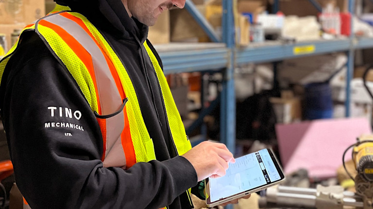 a person in a hard hat and vest looking at a tablet
